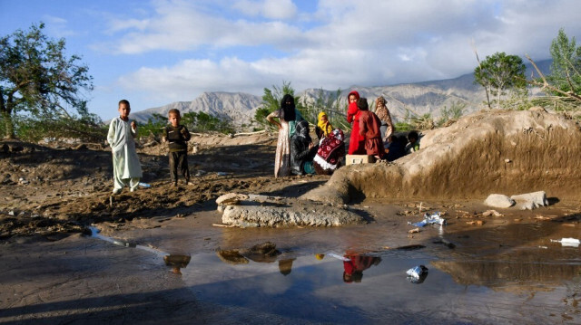 Des Afghans se tiennent près de maisons endommagées après les inondations dans la province de Baghlan, en Afghanistan, le 12 mai 2024. 