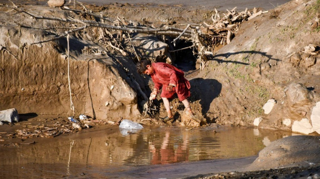 Un garçon marche dans les eaux boueuses après des inondations dans le district de Burka de la province de Baghlan le 12 mai 2024 en Afghanistan.