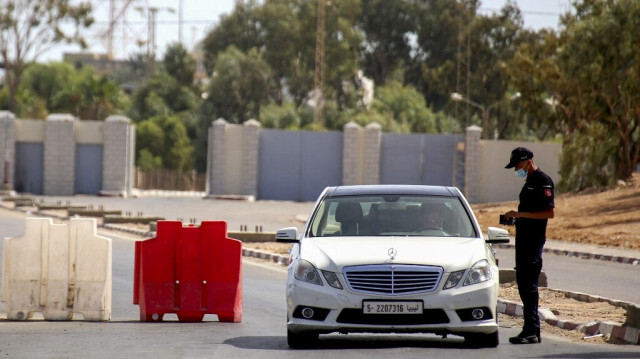 Un membre de la police tunisienne contrôle un citoyen libyen conduisant sa voiture vers la frontière libyenne, au poste frontière de Ras Jdir, dans le sud-est de la Tunisie, qui a été rouvert le 17 septembre 2021, après deux mois de fermeture en raison de la pandémie de Covid-19.