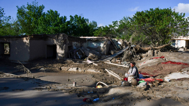 Un Afghan est assis près de maisons endommagées après des inondations dans la province de Baghlan, le 12 mai 2024. 