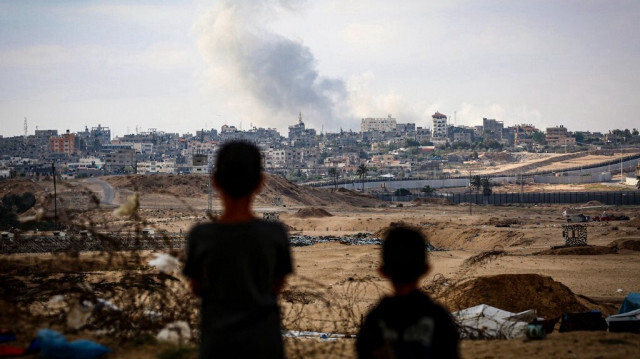 Des enfants Palestiniens regardent la fumée qui se dégage des frappes israéliennes à l'est de Rafah, dans le sud de la Bande de Gaza, le 13 mai 2024.