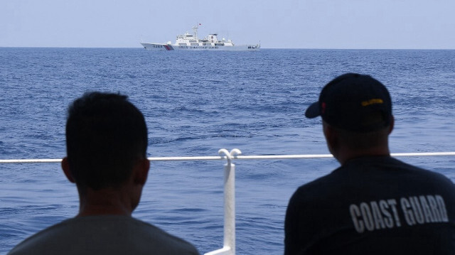 Le personnel des garde-côtes philippins à bord du BRP Bagacay observe un navire des garde-côtes chinois lors de la distribution de carburant et de nourriture aux pêcheurs par la mission civile Atin Ito (Ceci est à nous) Coalition, dans la mer de Chine méridionale contestée, le 16 mai 2024.