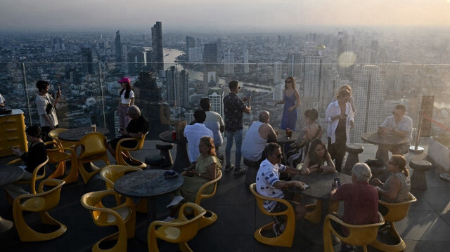 Des touristes et des habitants de Bangkok regardent la vue de la ville depuis le pont d'observation du Mahanakhon Skywalk à Bangkok, le 14 mai 2024.