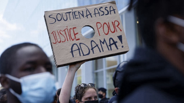 Un manifestant brandit une pancarte sur laquelle on peut lire "Soutien à Assa, justice pour Adama" lors du procès d'Assa Traoré, la sœur d'Adama Traoré, devant le palais de justice "Tribunal de Paris" à Paris, le 7 mai 2021.