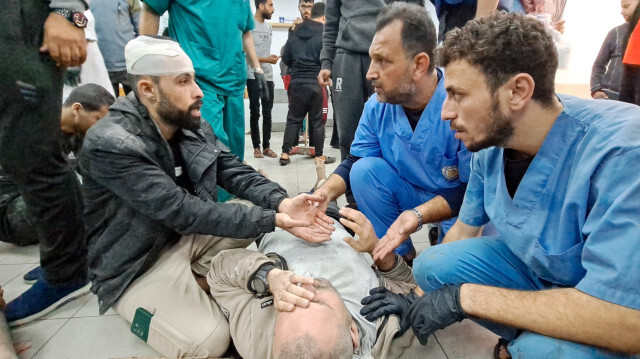 Des médecins palestiniens écoutant un homme alors que les blessés sont amenés à l'hôpital Kamal Adwan à Beit Lahia après un bombardement israélien, le 21 novembre 2023, dans le cadre des batailles entre Israël et le mouvement palestinien Hamas.