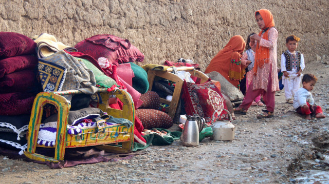 Une femme afghane (à gauche) et ses enfants sont assis à côté de leurs affaires conservées près d'une maison endommagée par des inondations soudaines suite à de fortes pluies à Firozkoh, dans la province de Ghor, le 18 mai 2024. 