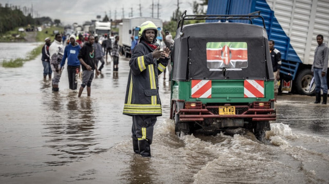 Un pompier kenyan donne des indications aux usagers alors que des résidents inspectent une route fortement touchée par les inondations suite à des pluies torrentielles à Kitengela, le 1er mai 2024. 