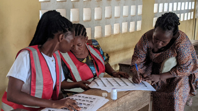 Les responsables électoraux s'occupent d'un électeur dans un bureau de vote à l'école primaire publique de Hedzranawoe à Lomé le 29 avril 2024, lors des élections législatives au Togo.