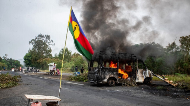 Un drapeau kanak près d'un véhicule en feu lors d'un barrage routier indépendantiste à La Tamoa, dans la commune de Paita, en Nouvelle-Calédonie, territoire français du Pacifique, le 19 mai 2024.