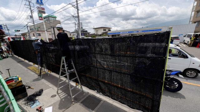 Des ouvriers installent une barrière pour bloquer la vue du Mont Fuji du Japon émergeant de derrière une supérette pour dissuader les touristes mal élevés, dans la ville de Fujikawaguchiko, préfecture de Yamanashi, le 21 mai 2024.
