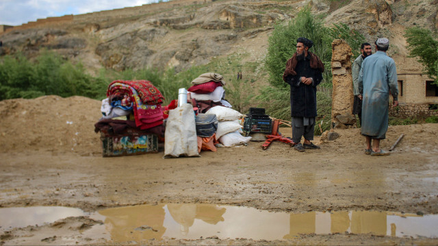 Des hommes afghans se tenant à côté de leurs affaires conservées près d'une maison endommagée à la suite d'inondations soudaines consécutives à de fortes pluies à Firozkoh, dans la province de Ghor, le 18 mai 2024. 
