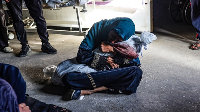 Une femme palestinienne tient le corps enveloppé d'un enfant tué lors d'un bombardement israélien, dans une clinique de la région de Tel al-Sultan à Rafah, dans le sud de la bande de Gaza, le 26 mai 2024.