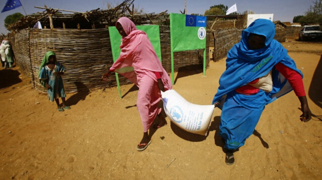Des femmes soudanaises portent un sac d'aide au camp El-Riyadh pour les personnes déplacées à l'intérieur du pays (IDP) à Geneina, la capitale de l'État du Darfour occidental du Soudan.