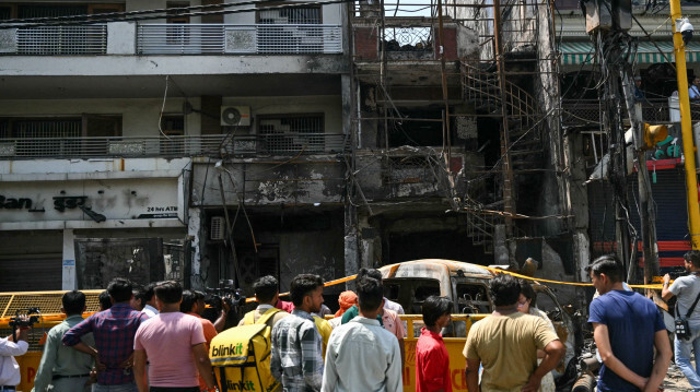Des hommes se rassemblant près des restes d'un site d'accident un jour après l'incendie d'un hôpital pour enfants à New Delhi, le 26 mai 2024. Six nouveau-nés sont morts après l'incendie d'un hôpital pour enfants dans la capitale indienne. Des personnes se sont jetées dans les flammes pour sauver les enfants, a déclaré la police le 26 mai.