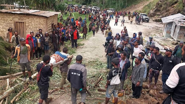 Des habitants transportant une personne sur une civière depuis le site d'un glissement de terrain au village de Yambali dans la région de Maip Mulitaka, dans la province d'Enga en Papouasie-Nouvelle-Guinée, le 25 mai 2024.