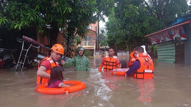 Les garde-côtes philippins, des enfants sont évacués d'une zone inondée par le personnel des garde-côtes à Lucena, dans la province de Quezon, au milieu des fortes pluies provoquées par la tempête tropicale Ewiniar, le 26 mai 2024.