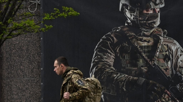 Un soldat ukrainien devant une affiche de recrutement à Kiev le 23 avril 2024, lors du conflit russo-ukrainien. 