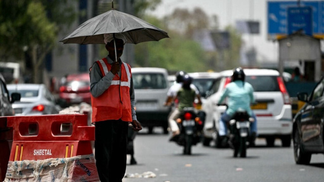 Un employé d'un poste de péage qui dirige la circulation se met à l'ombre sous un parapluie lors d'une chaude après-midi d'été à New Delhi, le 29 mai 2024, en raison de la vague de chaleur qui sévit actuellement.