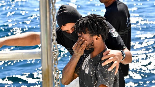 Un migrant d'origine africaine est réconforté par un membre des garde-côtes tunisiens après avoir été transféré d'un petit bateau transportant des personnes tentant de fuir vers l'Europe, en mer entre la Tunisie et l'Italie, le 10 août 2023. 