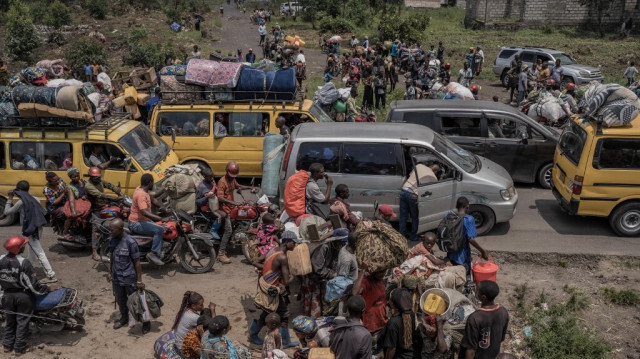 Des personnes se rassemblent sur une route fréquentée tout en transportant certains de leurs biens alors qu'elles fuient le territoire de Masisi suite aux affrontements entre les rebelles du M23 et les forces gouvernementales, sur une route près de Sake, le 7 février 2024.