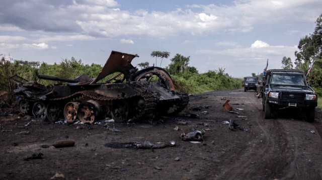 Des voitures passant devant un véhicule militaire détruit à Rugari, après des affrontements entre l'armée congolaise et les rebelles du M23 dans l'est de la République démocratique du Congo.