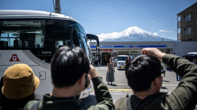 Des touristes prennent des photos du mont Fuji depuis la rue opposée d'un dépanneur où une immense barrière noire sera installée pour bloquer la vue du mont Fuji, dans la ville de Fujikawaguchiko, préfecture de Yamanashi.