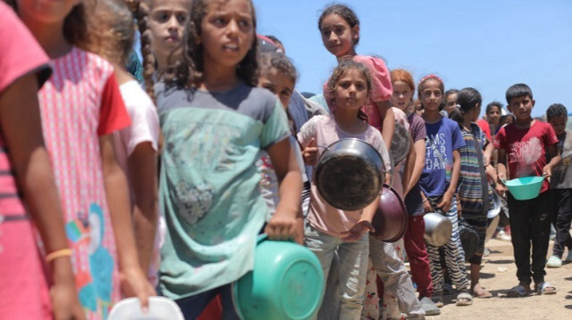 Des Palestiniens, dont des enfants, attendent pour recevoir de la nourriture distribuée par des organisations caritatives à Gaza.