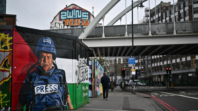 Un piéton passant devant un graffiti réalisé par l'artiste de rue espagnol Nacho Welles, également connu sous le nom de Core246, représentant le journaliste palestinien et chef de bureau d'Al Jazeera dans la ville de Gaza, Wael al-Dahdouh, dans le cadre d'un projet lancé par la plateforme artistique Creative Debuts intitulé "Héros de la Palestine", dans l'est de Londres, le 29 janvier 2024. Le chef du bureau d'Al Jazeera à Gaza, Wael al-Dahdouh, a quitté le territoire palestinien le 16 janvier 2024, a-t-il déclaré, après que des frappes israéliennes ont tué sa femme, plusieurs de ses enfants et un collègue. 