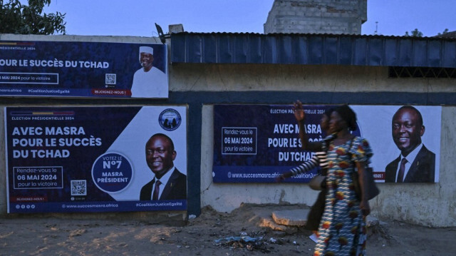 Piétons passent devant l'affiche de campagne de Succes Masra, candidat à l'élection présidentielle et premier ministre du Tchad, à N'Djamena le 3 mai 2024.