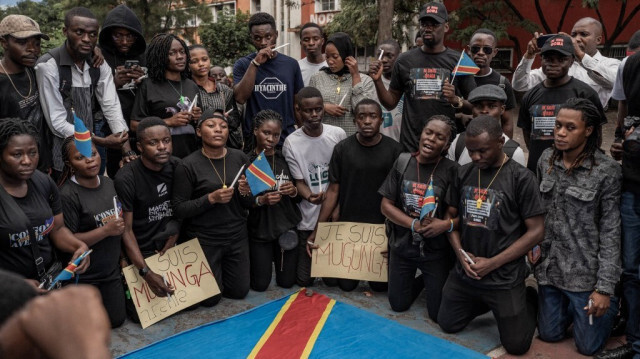 Des personnes se rassemblent autour d'un drapeau de la République démocratique du Congo lors d'un deuil collectif organisé par les mouvements citoyens en mémoire des victimes de l'attentat au camp de déplacés de Bulengo, au stade de l'ISC (institut supérieur de commerce) à Goma le 6 mai 2024. 