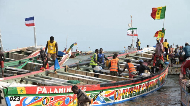 Des personnes débarquent de canots pneumatiques sur un quai de pêche, à Mbour, le 13 juillet 2023.