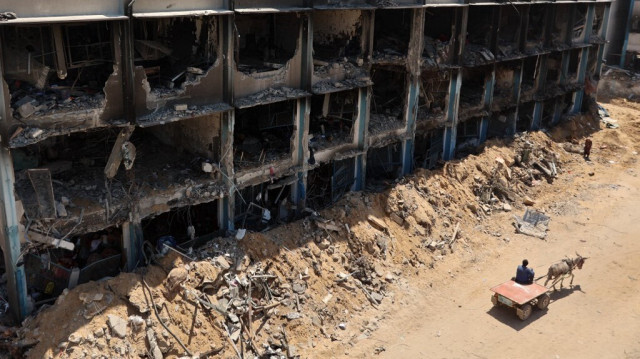 Un Palestinien passe avec une charrette tirée par un âne devant une école endommagée gérée par l'ONU dans le camp de réfugiés de Jabalia, dans le nord de la bande de Gaza, après être revenu brièvement avec d'autres personnes qui cherchaient à vérifier leurs maisons, le 31 mai 2024.