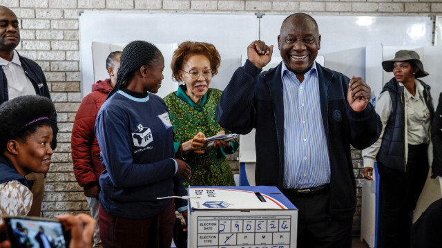 Le président du Congrès national africain (ANC) et président sud-africain Cyril Ramaphosa (2e R) réagit après avoir déposé son bulletin de vote au bureau de vote de l'école primaire Hitekani à Soweto, le 29 mai 2024, lors des élections générales en Afrique du Sud.