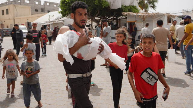 Un Palestinien portant le corps d'un enfant tué lors d'un bombardement israélien sur une maison dans la ville de Nuseirat à leur arrivée à l'hôpital Al-Aqsa Martyrs à Deir al-Balah, dans le centre de la bande de Gaza, le 27 mai 2024, alors que les combats se poursuivent entre Israël et le groupe militant palestinien du Hamas.