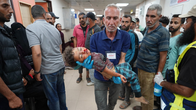 Un homme transportant un enfant palestinien, Khaled Abu Samaha, à l'hôpital Al-Aqsa Martyrs, dans le centre de la bande de Gaza, après qu'il ait été gravement blessé lors d'un bombardement israélien sur une maison dans la ville de Nuseirat, le 27 mai 2024, alors que les combats se poursuivent entre Israël et le groupe militant palestinien du Hamas.