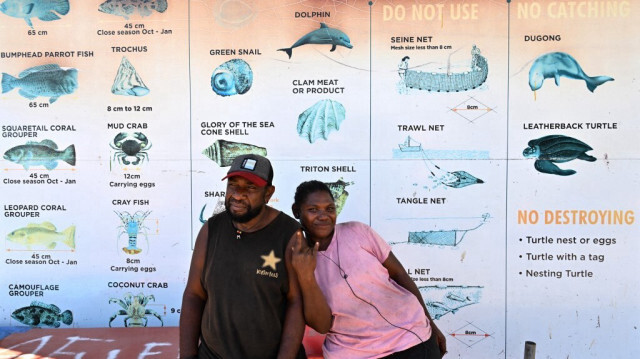 Des habitants devant un panneau mettant en garde les vendeurs contre le commerce d'animaux vivants, y compris les dauphins en tant qu'espèce "non vendue", au marché central d'Honiara, la capitale des Îles Salomon le 21 avril 2024.