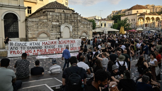 Des manifestants, des touristes et des passants devant des banderoles de soutien aux victimes du naufrage meurtrier d'un bateau de migrants, au large de la péninsule grecque du Péloponnèse, sur lesquelles on peut lire "Pylos a été un meurtre de masse commis par l'État grec et l'Union européenne", sur la place centrale Monastiraki d'Athènes, en Grèce, le 28 juin 2023.