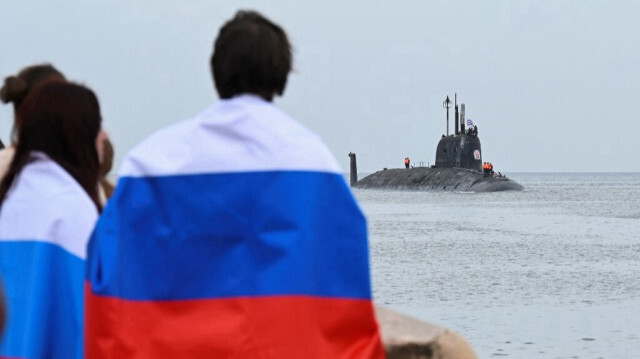 Des personnes portant des drapeaux russes regardent le sous-marin à propulsion nucléaire, Kazan, qui fait partie du détachement naval russe arrivant au port de La Havane, à Cuba, le 12 juin 2024.