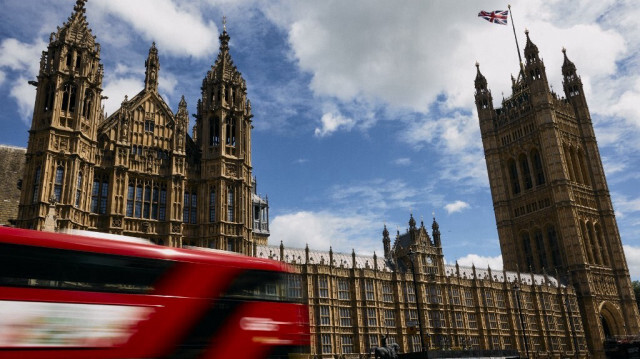 Un bus londonien à impériale passe devant le Palais de Westminster, qui abrite les Chambres du Parlement, dans le centre de Londres, le 14 juin 2024. 