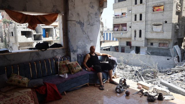 Un Palestinien est assis sur un canapé avec les restes de munitions explosées à ses pieds dans un appartement partiellement détruit, dans le camp de réfugiés de Nuseirat, dans le centre de la bande de Gaza, le 15 juin 2024.