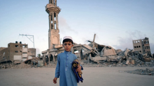 Un garçon palestinien portant son tapis de prière pose pour une photo avant de se joindre à la prière matinale de l'Aïd al-Adha à Khan Yunis dans le sud de la bande de Gaza, le 16 juin 2024.