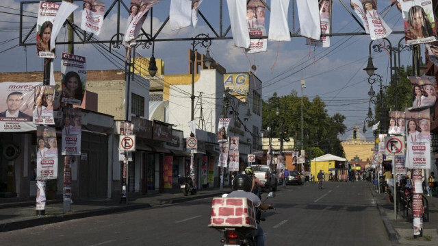 Des motocyclistes passent sous une bannière de campagne électorale à Xochimilco, au Mexique, le 31 mai 2024.