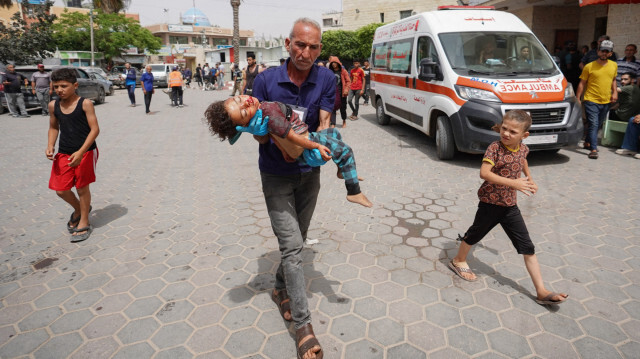 Un homme transportant un enfant palestinien, Khaled Abu Samaha, à l'hôpital Al-Aqsa Martyrs, dans le centre de la bande de Gaza, après qu'il ait été blessé lors d'un bombardement israélien sur une maison dans la ville de Nuseirat, le 27 mai 2024, alors que les combats se poursuivent entre Israël et le groupe militant palestinien du Hamas.