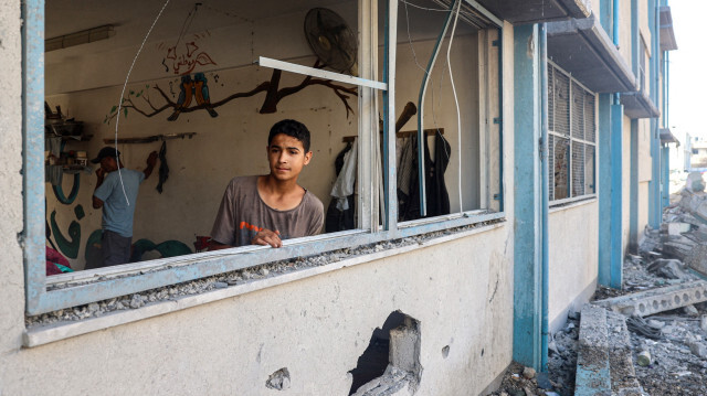 Un garçon palestinien se tenant près d'une fenêtre brisée dans une école de l'ONU abritant des personnes déplacées qui a été endommagée lors d'un bombardement israélien à Khan Yunis le 21 juin 2024, dans le sud de la bande de Gaza, dans le cadre du conflit en cours dans le territoire palestinien entre Israël et le Hamas.