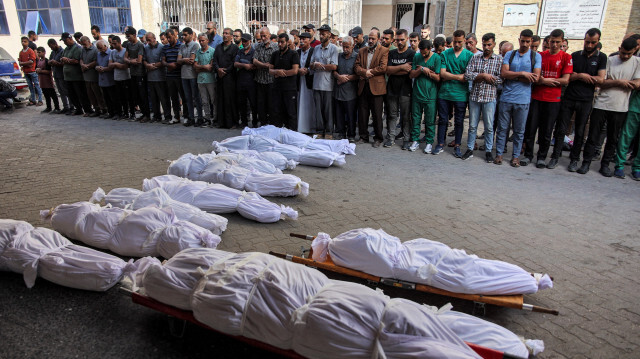 Des hommes priant près des corps enveloppés des victimes qui ont été tuées lors des bombardements israéliens de la nuit précédente à l'hôpital Ahli Arab dans la ville de Gaza, le 14 juin 2024, dans le cadre du conflit en cours dans le territoire palestinien entre Israël et le Hamas.
