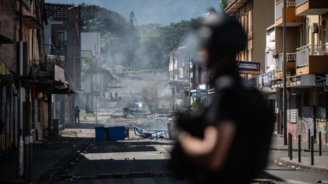 La police française au milieu de débris, près d'un barrage routier mis en place par les partisans de l'indépendance lors d'une opération dans le quartier de la Vallée du Tir à Nouméa sur le territoire français du Pacifique de la Nouvelle-Calédonie, le 24 juin 2024.