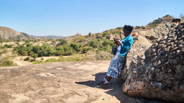 Sakhile Sibindi utilise son téléphone portable à Matobo, Matabeleland, le 10 mai 2024. Silozwe, un village situé à moins de 50 km de Bulawayo, la deuxième ville du sud du pays, est une zone d'ombre pour les réseaux téléphoniques. 