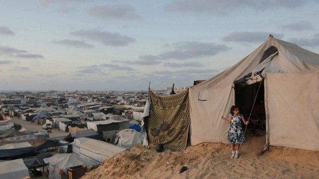 Палестинская девочка стоит у входа в палатку для перемещенных лиц в результате израильского наступления на сектор Газа в Хан-Юнисе, 18 июня 2024 года. 