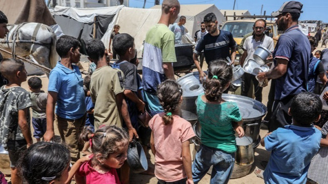 Les Palestiniens, y compris les enfants, attendent en file avec leurs récipients pendant que les organisations humanitaires distribuent des repas dans la Bande de Gaza.