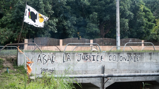 Un drapeau indépendantiste et un graffiti "à bas la justice coloniale" ornent un pont près du Mont-Dore, dans la banlieue de Nouméa, sur le territoire français du Pacifique de la Nouvelle-Calédonie, le 25 juin 2024.